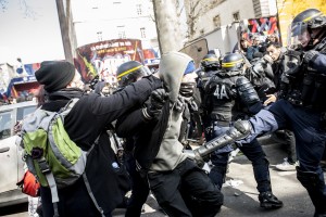 Un policer assène un coup de pied à un manifestant demandant la libération de ses camarades pris dans la nasse.