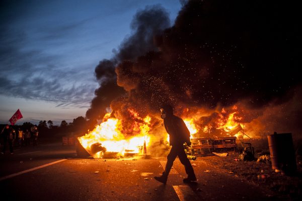 blocage devant le dépôt pétrolier de Douchy-les-Mines. Un manifestant traverse la route devant les barricades en feu.