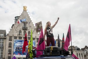 Une manifestante, debout sur la camionette de SUD, chante des slogans avec la foule le poing levé