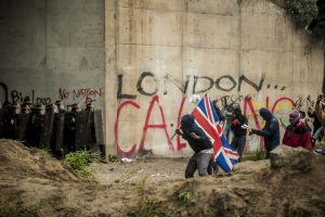 Manifestation en faveur des réfugiés. 1er octobre 2016 – Calais. Des réfugiés se rapprochent de la ligne de CRS drapeau britannique à la main. Pays vers lequel les réfugiés demandent l’ouverture des frontières.