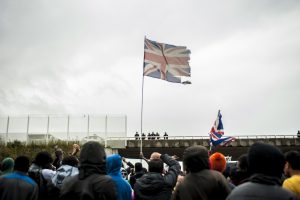 Manifestation en faveur des réfugiés. 1er octobre 2016 – Calais. Un drapeau britannique flotte au dessus du rassemblement. La plupart des réfugiés souhaitent rejoindre la Grande Bretagne.