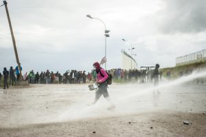 Manifestation en faveur des réfugiés. 1er octobre 2016 – Calais. Un musicien de la batucada est arrosé par la canon à eau. Quelques minutes plus tard, il sera arrêté par la police lors d’une charge.