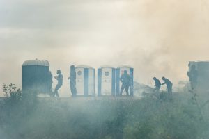 Manifestation en faveur des réfugiés. 1er octobre 2016 – Calais. Les réfugiés se protègent des grenades et des tirs de LBD derrière les toilettes de l’entrée de la jungle.
