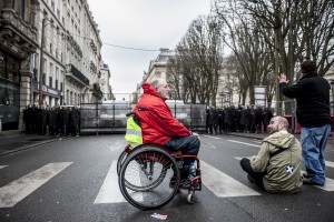 Une personne handicapée reste campée devant la police en fin de manifestation.