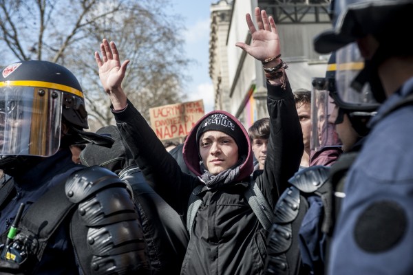Un lycéen dans une nasse lève les bras en signe de non violence.