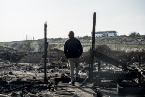 Le démantèlement de la zone sud de la jungle de Calais arrive à sa fin. Un réfugié observe la route sur les cendres d’un ancien restaurant de la jungle.