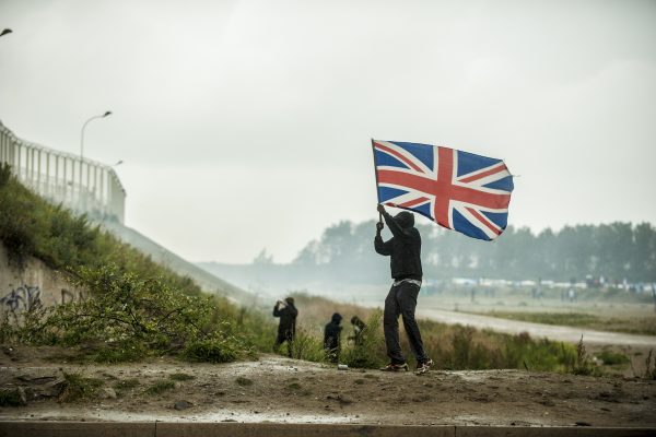 Manifestation en faveur des réfugiés. 1er octobre 2016 – Calais. Un réfugié se rapproche de la ligne de CRS drapeau britannique à la main. Pays vers lequel les réfugiés demandent l’ouverture des frontières.