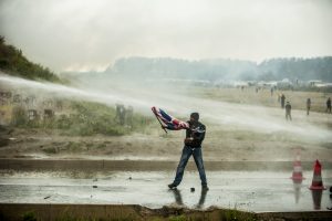 Manifestation en faveur des réfugiés. 1er octobre 2016 – Calais. Un réfugié tenant un drapeau britannique à la main est repoussé par le canon à eau