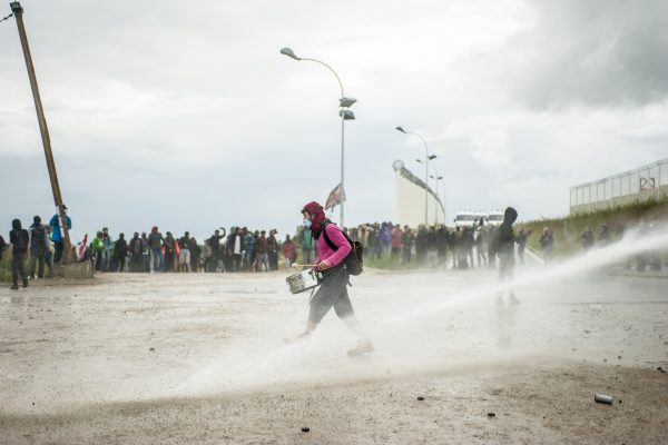 Manifestation en faveur des réfugiés. 1er octobre 2016 – Calais. Un musicien de la batucada est arrosé par la canon à eau. Quelques minutes plus tard, il sera arrêté par la police lors d’une charge.